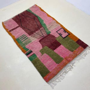 a colorful, abstract rug with a geometric pattern in shades of pink, green, and orange.
