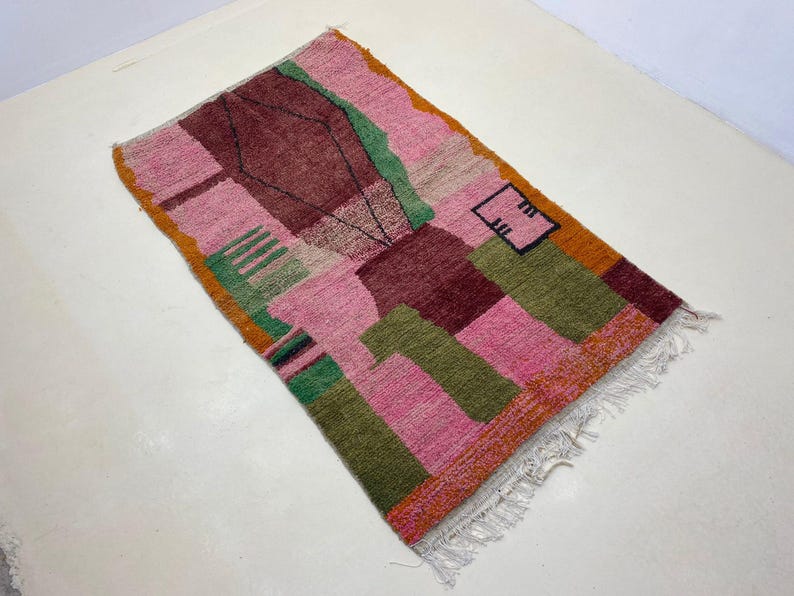 a colorful, abstract rug with a geometric pattern in shades of pink, green, and orange.