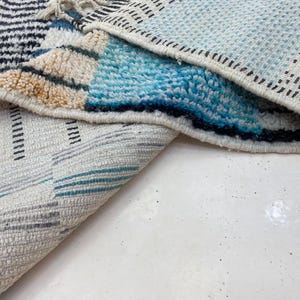 a close-up view of a colorful rug with a geometric pattern, featuring a mix of blue, white, and black colors.