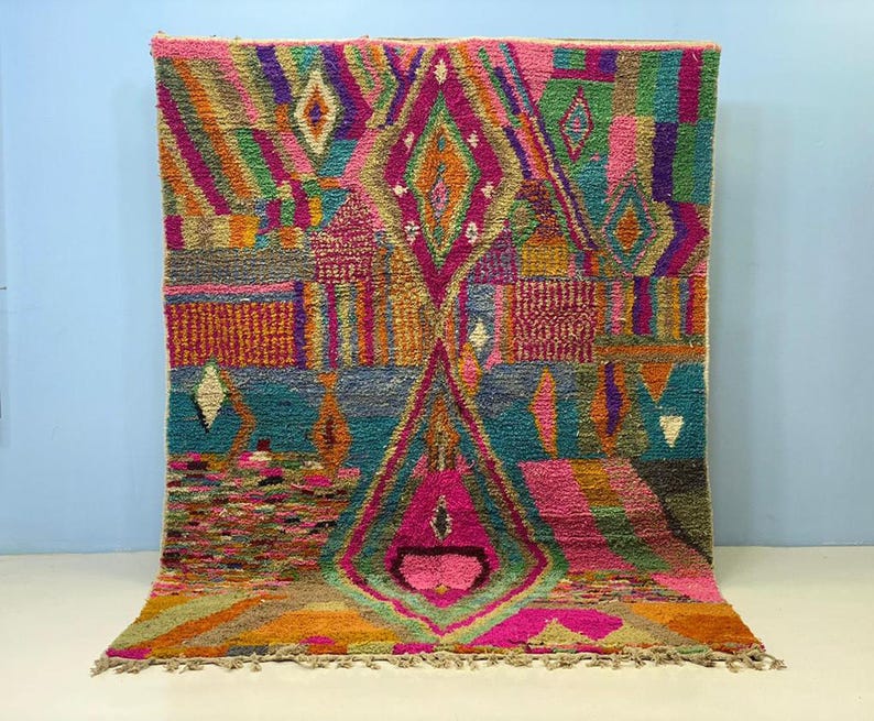a vibrant, colorful rug with a geometric pattern and a variety of shapes and colors, including shades of pink, green, blue, and orange.