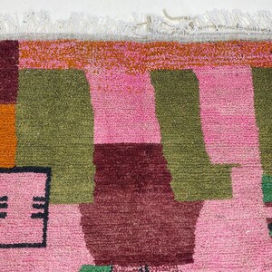 a vibrant, colorful rug with a geometric pattern in shades of pink, green, and orange.