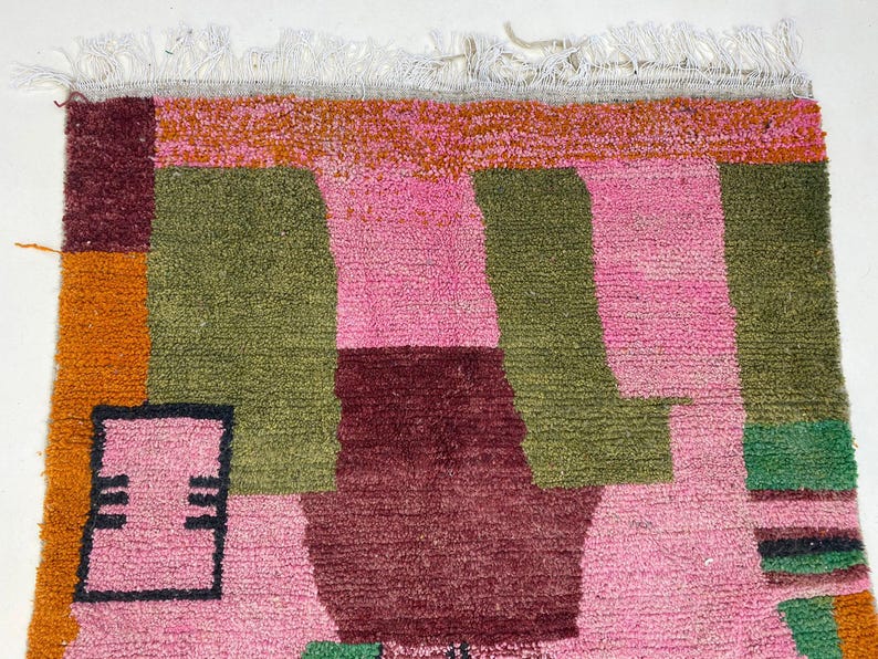 a vibrant, colorful rug with a geometric pattern in shades of pink, green, and orange.