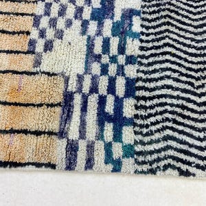 a close-up view of a colorful, patterned rug with a mix of stripes, checkered designs, and zigzag patterns.