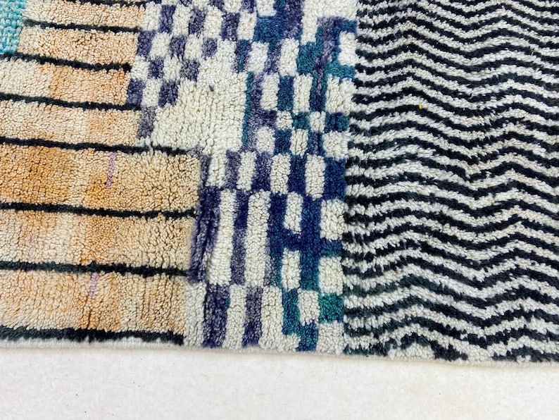 a close-up view of a colorful, patterned rug with a mix of stripes, checkered designs, and zigzag patterns.
