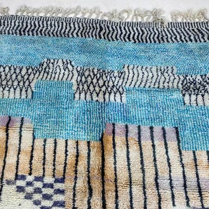 a colorful, patterned rug with a mix of blue, black, and white stripes and geometric shapes.