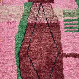 a vibrant, colorful rug with a geometric pattern in shades of pink, green, and red.