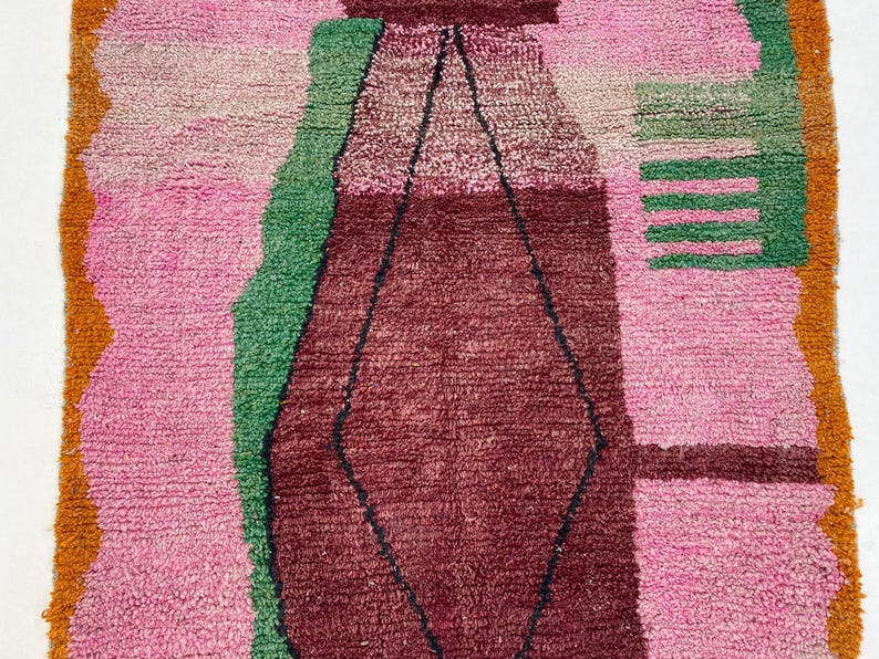 a vibrant, colorful rug with a geometric pattern in shades of pink, green, and red.