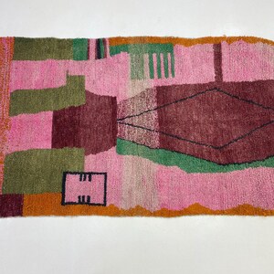 a vibrant, colorful rug with a geometric pattern in shades of pink, green, and orange.
