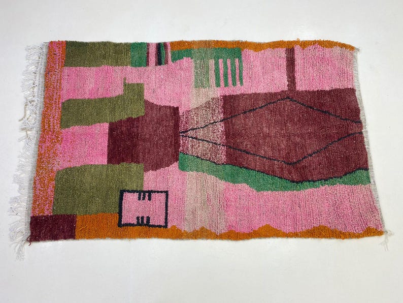 a vibrant, colorful rug with a geometric pattern in shades of pink, green, and orange.