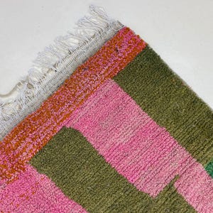 a colorful rug with a geometric pattern of pink, green, and orange squares.