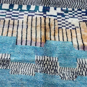 a vibrant and colorful rug with a geometric pattern of stripes and blocks in various shades of blue, orange, and black.
