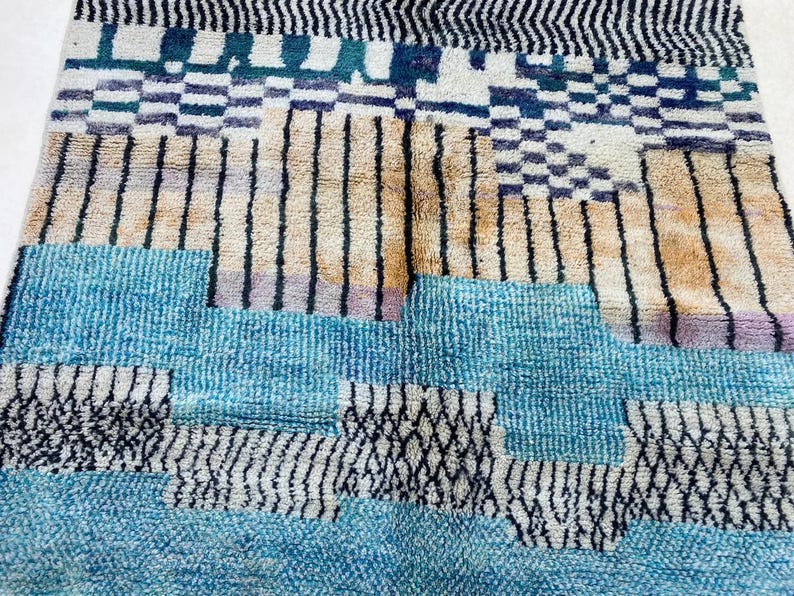 a vibrant and colorful rug with a geometric pattern of stripes and blocks in various shades of blue, orange, and black.