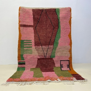 a vibrant, colorful rug with a geometric pattern in shades of pink, green, and orange.