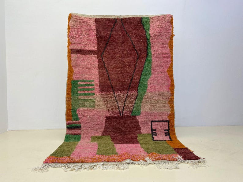 a vibrant, colorful rug with a geometric pattern in shades of pink, green, and orange.