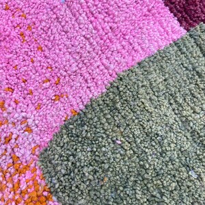 a close-up view of a colorful, textured carpet with a variety of pink, green, and orange hues.