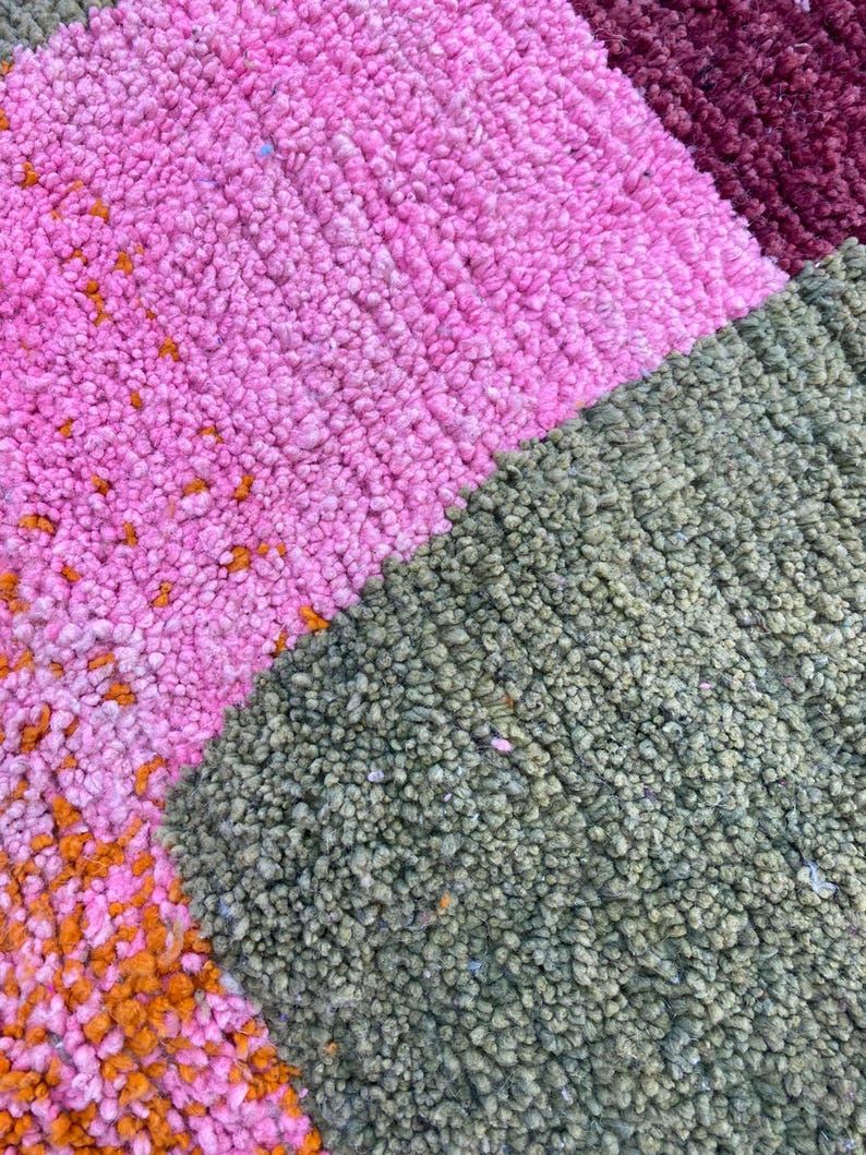 a close-up view of a colorful, textured carpet with a variety of pink, green, and orange hues.
