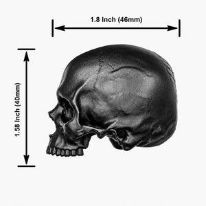 May include: A matte black skull figurine shown in profile. Dimension lines indicate a width of 1.8 inches and a height of 1.58 inches. The skull features detailed anatomical contours including the eye socket, nasal cavity, and teeth.