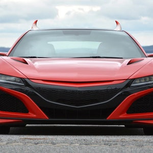 May include: A red sports car with devil horns on the front. The car has a black grille and headlights.