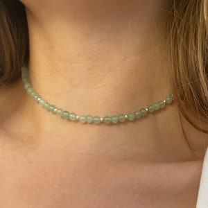 Puede incluir: Un delicado collar de choker de piedra verde con cuentas plateadas.