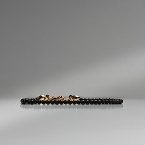 Peut inclure: Un bracelet en perles noires avec un fermoir en or.
