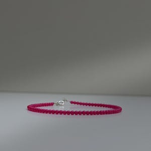 Può includere: Un delicato braccialetto di perline con piccole perle rotonde color fucsia. Il braccialetto è assicurato con una chiusura color argento. Le perle sono uniformemente distanziate, creando un design semplice ma elegante.