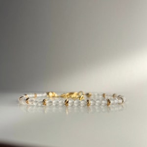 Pode incluir: Um bracelete delicado feito de contas facetadas transparentes com detalhes dourados. O bracelete é simples e elegante, perfeito para o uso diário.