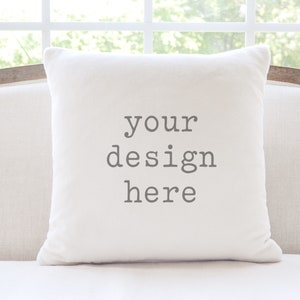 May include: White throw pillow with the text "your design here" printed in gray on the front.