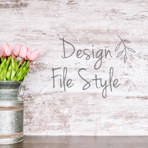 Puede incluir: Tulipanes rosas en un jarrón de metal galvanizado en forma de lechera sobre un fondo de madera blanqueada. El texto "Design File Style" está escrito en gris sobre la madera.