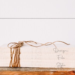 May include: A stack of three white books wrapped with twine. The books are labeled "Design", "File", and "Style".