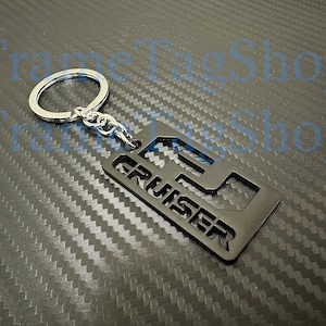May include: Black metal keychain with a cutout of the word "CRUISER" and a key ring.