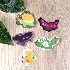 May include: A collection of colorful cartoon stickers featuring various creatures. The stickers include a green turtle with a yellow shell, a purple bug-like creature, a brown mushroom, a green rabbit-like character, and a yellow Pikachu.