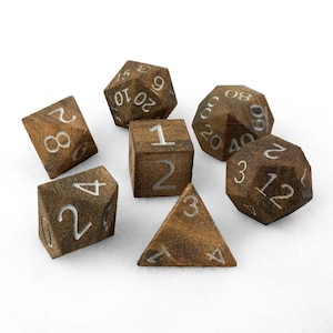 Op de afbeelding: Een set van zes houten dobbelstenen met witte nummers. De dobbelstenen zijn in verschillende vormen, waaronder een kubus, een piramide en een dodecaëder. De dobbelstenen zijn allemaal bruin en hebben een ruw, getextureerd oppervlak.