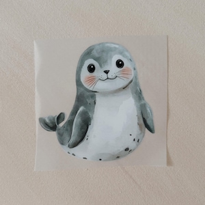 Könnte beinhalten: Ein niedlicher Cartoon-Seehund mit grauem Fell, weißem Bauch und schwarzen Augen. Der Seehund hat eine rosa Nase und einen kleinen Mund mit einem Lächeln. Der Seehund sitzt auf einem weißen Hintergrund.