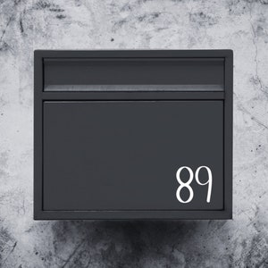 Puede incluir: Un buz&oacute;n de metal negro con el n&uacute;mero 89 impreso en blanco en la parte delantera.