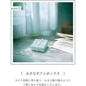 May include: A small, pale blue gift box with a cream ribbon on a wooden surface. An open book with white pages is next to the box. The text "point 2" is in the upper left corner. The box is a charming present.