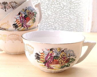 May include: Set of four white teacups with gold trim and a colorful Japanese-inspired design featuring women in traditional clothing and a mountain landscape.