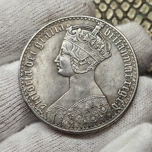 Może przedstawiać: Srebrna moneta z profilowym portretem królowej Wiktorii w koronie. Inskrypcja na brzegu głosi "Victoria Dei Gratia Britanniarum Regina".