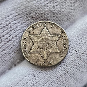 Puede incluir: Moneda de plata de los Estados Unidos de América con un diseño de estrella de seis puntas y el año 1872.