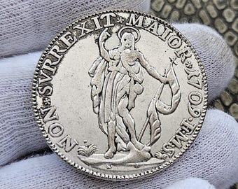 May include: Silver coin with a raised image of a person holding a banner with the text "NON SVREXIT MAIOR REX" around the edge.