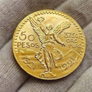 Puede incluir: Una moneda de oro mexicana de 50 pesos con la figura alada del Ángel de la Independencia, con la inscripción "50 PESOS 1821 1921 37.5G ORO PURO".