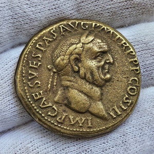 Puede incluir: Una moneda romana de oro con la inscripción "IMP CAES VESPASIAN AVG PM TR P COS IIII" alrededor del borde y un perfil de un hombre con una corona en la cabeza.