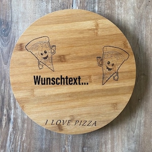 Puede incluir: Una tabla de cortar redonda de bambú marrón claro con el texto "I LOVE PIZZA". Dos personajes de dibujos animados de porciones de pizza están grabados en la tabla, junto con el texto "Wunschtext...".