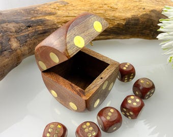Könnte beinhalten: Eine Würfelbox aus Holz mit einem Scharnierdeckel, der geöffnet ist, um das Innere freizugeben. Sechs rotbraune Würfel mit goldfarbenen Punkten sind um die Box herum verstreut. Die Box und die Würfel sind aus Holz mit polierter Oberfläche.