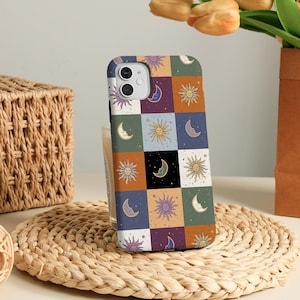 May include: A white phone case with a colorful pattern of suns and moons. The pattern is a patchwork of squares with different colors and designs.