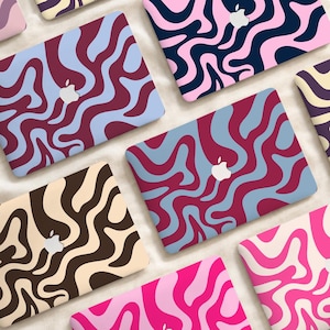 Op de afbeelding: Een collectie laptopskins met diverse golvende, vloeistofachtige patronen in verschillende kleurencombinaties, waaronder roze en donkerblauw, bordeauxrood en lichtblauw, en bruin en crème, elk met een uitsparing voor het Apple-logo.