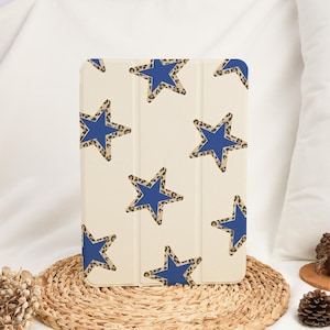 Puede incluir: Funda de tableta color crema con un patrón repetido de estrellas azules con bordes de estampado de leopardo. La funda cerrada está hecha de un material liso. El diseño es moderno y llamativo, adecuado para varios dispositivos.