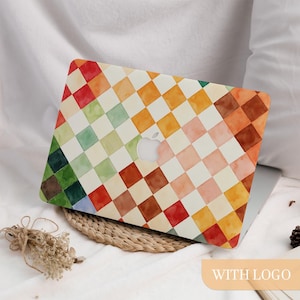 Puede incluir: Una funda de portátil colorida con un patrón de tablero de ajedrez de acuarela en tonos de rojo, naranja, amarillo, verde y marrón. La funda tiene un recorte para el logotipo de Apple. Las palabras "WITH LOGO" están en la esquina inferior derecha.