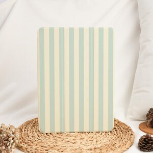 May include: A tablet case with a vertical striped pattern in light green and cream colors. The case is resting on a woven mat, with a white background.