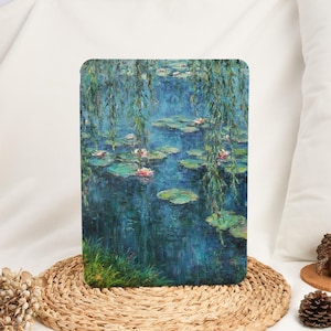 May include: A rectangular art print featuring a water lily pond scene with pink flowers, green lily pads, and weeping willow branches. The artwork has a blue and green color palette, reminiscent of a Monet painting.