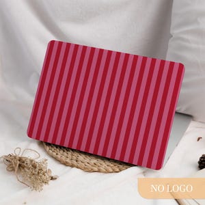 May include: A laptop case with a red and pink striped pattern. The case is rectangular and covers the top of a laptop. The stripes are vertical and evenly spaced. The case is on a white surface.